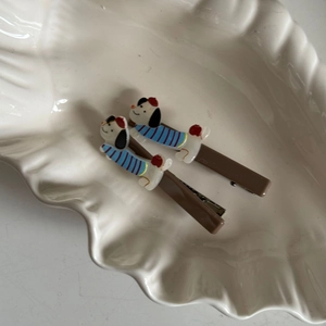 Detail van schattige cartoon honden haarspeldjes op een wit keramisch schelpvormig bord