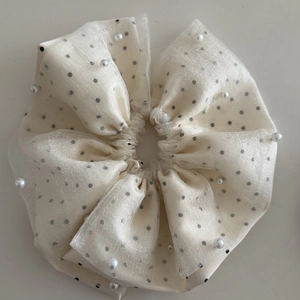Détail de chouchou en organza crème à pois avec perles élégantes pour cheveux