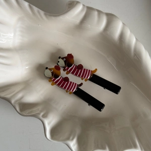 Detail van twee schattige teckel haarclips met rode truien in een witte schaal