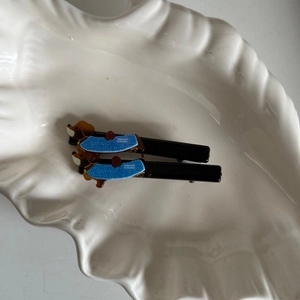 Detail van schattige acryl teckel haarspeldjes met blauwe vestjes in een keramieken schaal
