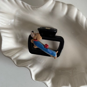 Detail van zwarte haarklem met een schattige cartoon teckel met denim gilet decoratie