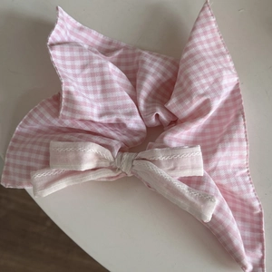 Detailed view of a pink plaid scrunchie with a ribbon bow and lace accents