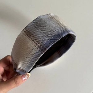 Detail shot of the woven plaid fabric texture on a wide-brimmed blue striped headband