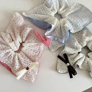 Détail de chouchous à carreaux avec dentelle blanche, nœuds en ruban et perles