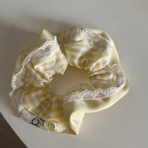 Close-up of yellow plaid hair scrunchie with white lace edges and decorative button
