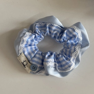 Detail of blue plaid hair scrunchie with lace trim and small bow label ornament
