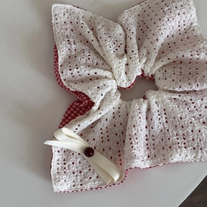 Détail d'un chouchou à carreaux rouges avec dentelle et élégant nœud en satin crème