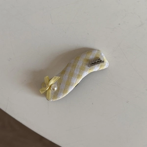 Detail of a handmade fabric hair clip with a yellow bow and pearl accent
