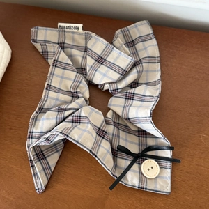 Plaid checkered scrunchie with button and bow detail on a rustic wood surface