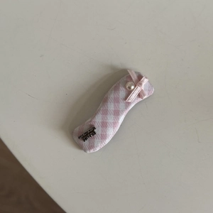 Detailed view of pink plaid hair clip with ribbon bow, faux pearl, and handmade metal tag