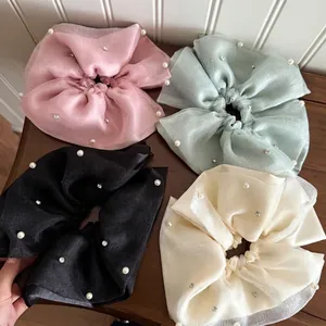 French tulle scrunchies set with pearls and rhinestones on a wooden background