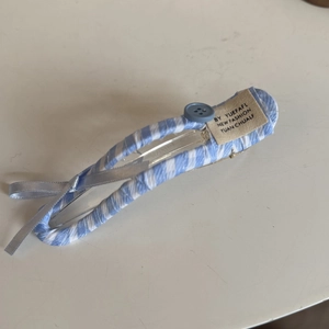 Detail showing blue and white striped fabric hair clip with button and silver ribbon bow
