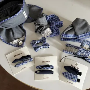 Detail view of blue and grey plaid fabric hair clips and lace scrunchies on white surface