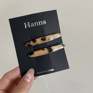 Detail of tortoise shell acetate hair clips with gold lettering on a display card