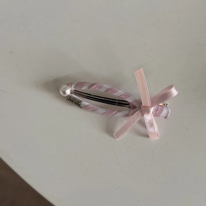 Detailed shot of pink striped ribbon hair clip with pearl bead and handmade engraving