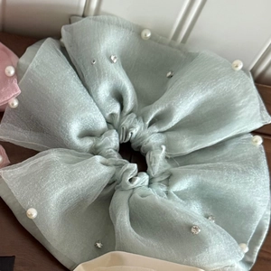 Detailed close-up of light green organza scrunchie with delicate pearls and crystals