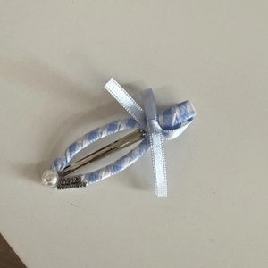 Detail of blue plaid ribbon hair clip with satin bow, faux pearl and metal tag charm
