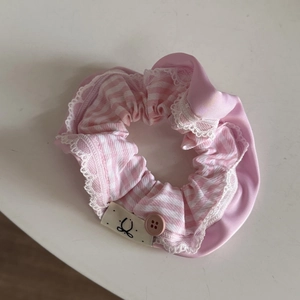 Detailed shot of pink striped scrunchie with lace trim and elegant resin button detail
