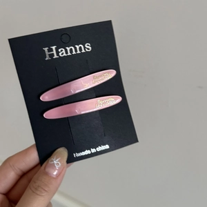 Detailed macro view of two pink pearlescent leaf hair clips on a black card