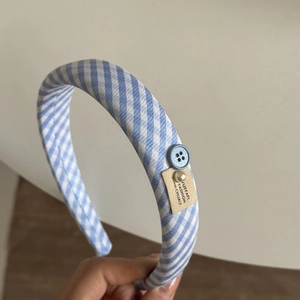 Detailed texture of blue plaid padded headband with button and pearl accents
