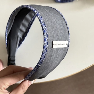 Detail of grey fabric headband with blue plaid piping and handmade woven label
