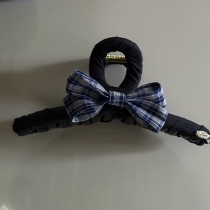 Detailed view of dark fabric hair claw clip with blue plaid bow and silver Love tag