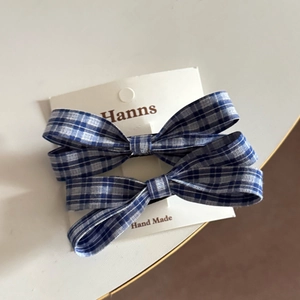 Close-up of handmade blue and white plaid bow hair clips on a professional display card