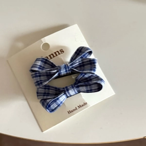 Close-up of blue plaid fabric bow hair clips set on a display card with handmade text