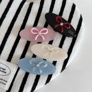 Détail de quatre barrettes en acétate avec nœuds et strass brillants aux couleurs pastel