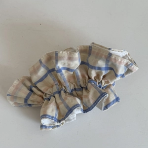Gros plan d'un chouchou à carreaux avec des motifs bleus et orange sur tissu crème