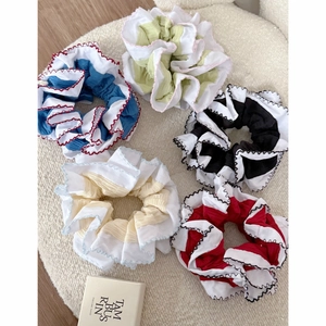 Detailed view of layered fabric scrunchies with white wave edges and contrast stitching
