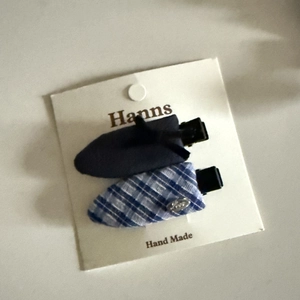 Detail of blue and plaid fabric bow hair clips with metallic accents on display card