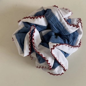 Macro detail of blue and white layered scrunchie with red wavy stitching and soft pleats