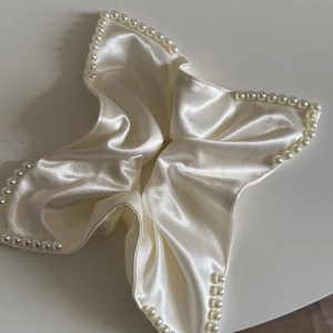 Macro detail of French beaded satin scrunchie showing ivory silk texture and faux pearls