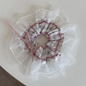 Détail de chouchou à carreaux roses avec dentelle à pois blancs et un nœud en ruban