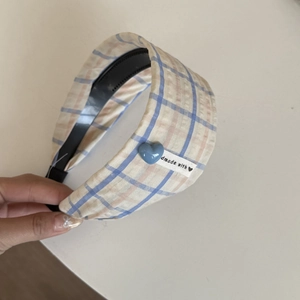 Gros plan d'un serre-tête large à carreaux avec étiquette faite main et détail de cœur bleu