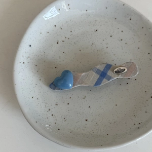 Détail d'une pince à cheveux en tissu écossais bleu avec cœur et plaque gravée Love