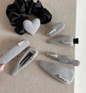 Macro view of grey fabric hair clip set with white pearls and heart satin scrunchie