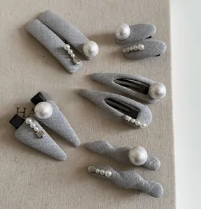 Detail of gray fabric hair clips with pearls and metal beads in multiple shapes