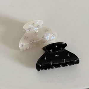 Detail of medium hair claws in cream and black with star rhinestone patterns