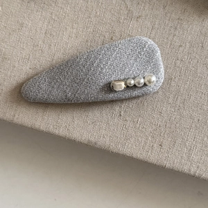 Close-up of grey tweed hair clip with three white pearls and a silver metal bead detail