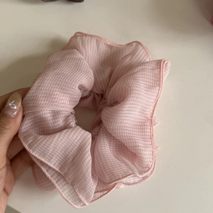 Rosafarbener Scrunchie aus Organza mit Karomuster auf einem neutralen weißen Hintergrund