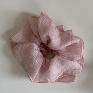 Detail eines rosa karierten Haargummis aus leichtem Stoff mit weicher Faltenstruktur