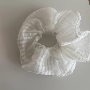 Detailaufnahme von weißem Organza-Haargummi mit geschichteter Stoffstruktur und Falten
