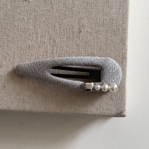 Detail of silver gray fabric hair clip featuring elegant pearls and metallic beads decoration