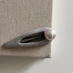 Detailed view of silver fabric BB hair clip with large lustrous white faux pearl