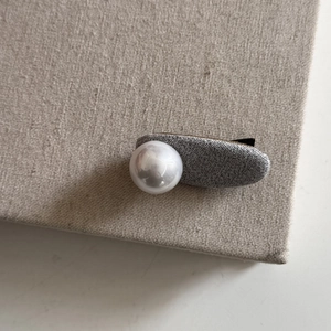 Detailed shot of grey fabric oval and large white pearl on an elegant hair clip