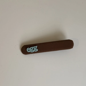Vue détaillée de la pince à cheveux en tissu à carreaux avec motif lettre egg bleu clair