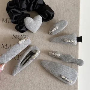 Grey tweed hair clip and pearl hairband set on a minimalist beige background