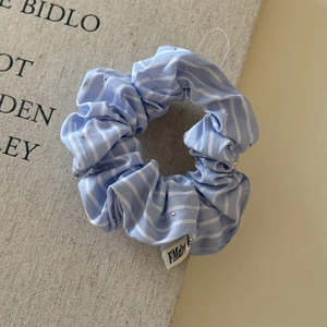 Détail du chouchou en tissu à rayures bleues avec perles argentées et étiquette tissée